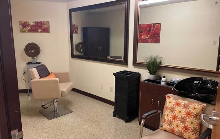 A cozy salon waiting area featuring comfortable chairs, large mirrors, and tasteful decor.