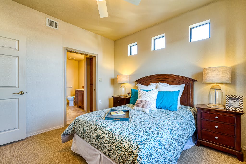A cozy bedroom with a comfortable bed, colorful pillows, and warm lighting.