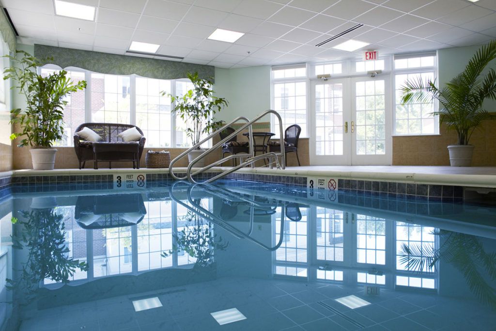 A serene indoor swimming pool area with natural light streaming through large windows.