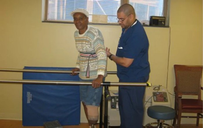 An elderly individual undergoes physical therapy with assistance from a healthcare professional.