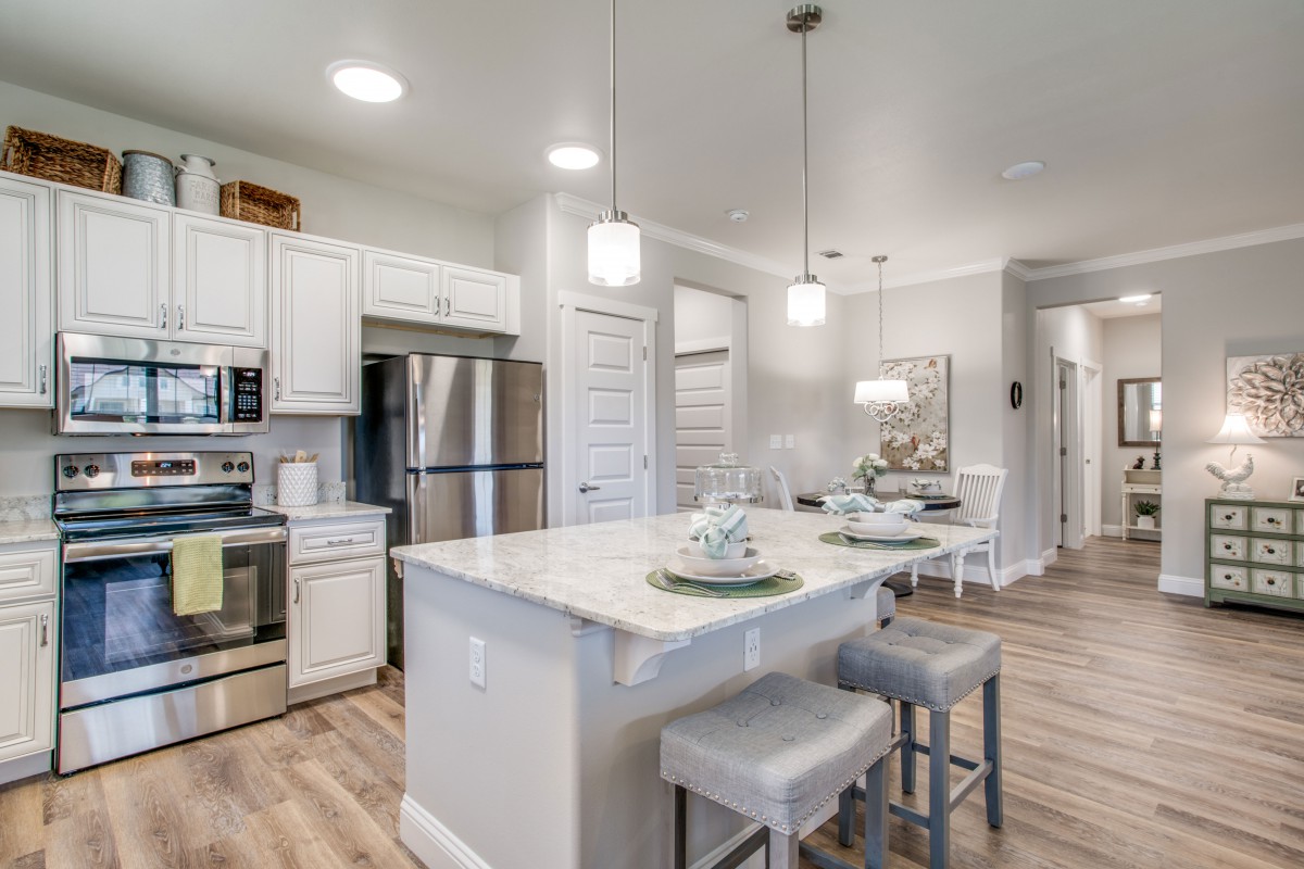 A modern kitchen with white cabinets, stainless steel appliances, and a central island with pendant lighting.