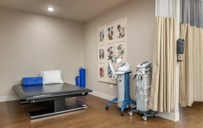 A clinical treatment room equipped with medical devices and a bed for patient care.