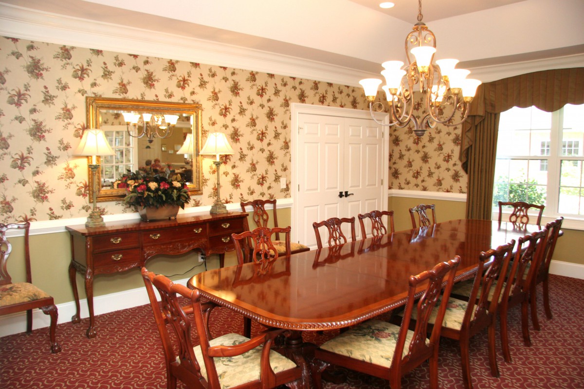 A classic dining room with a wooden table, elegant chairs, and a chandelier overhead.