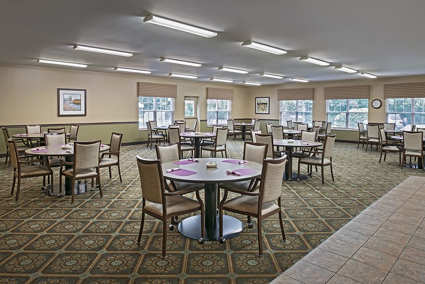 A spacious dining area with neatly arranged tables and chairs, featuring large windows and ample lighting.
