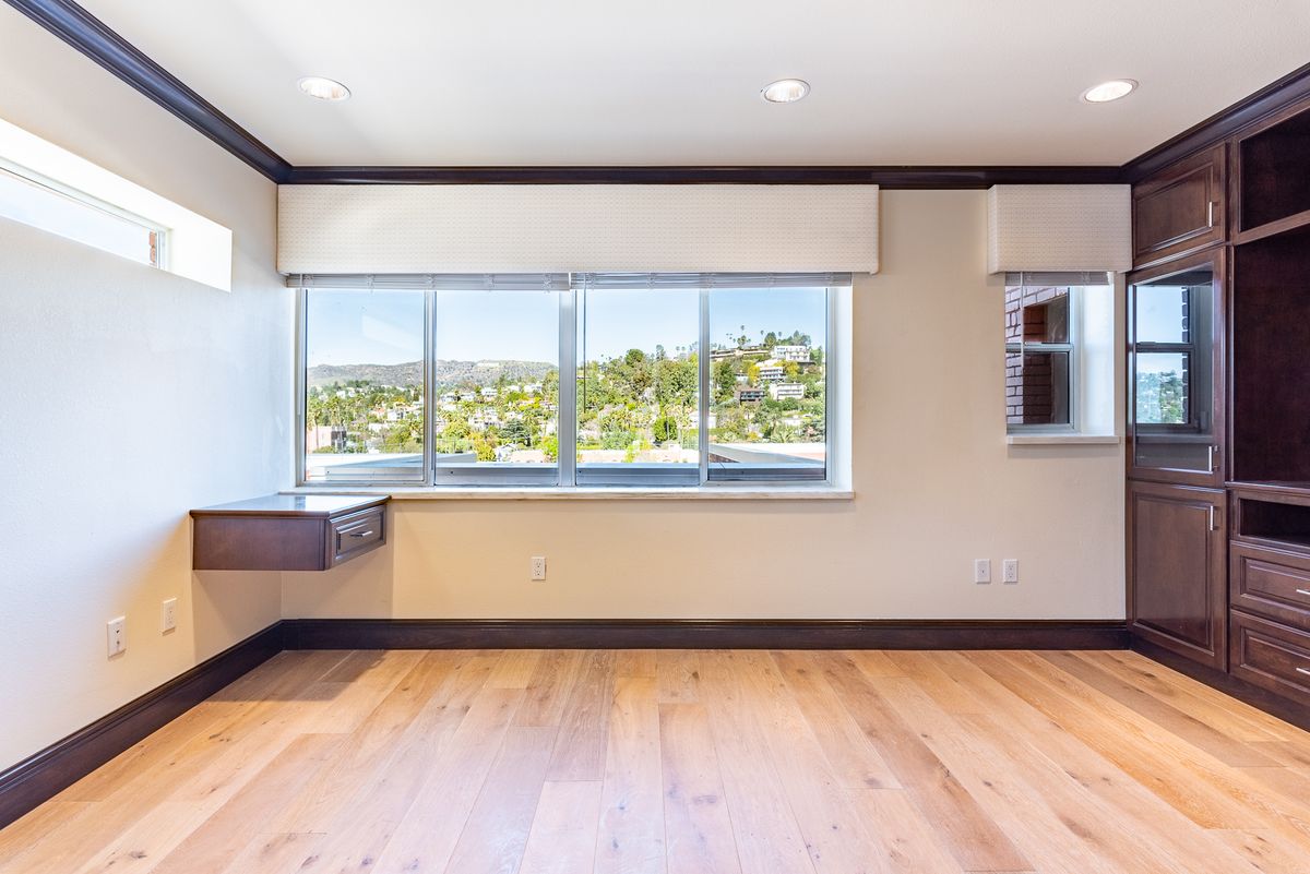 A bright and empty room with large windows and a wooden floor, showcasing modern interior design.