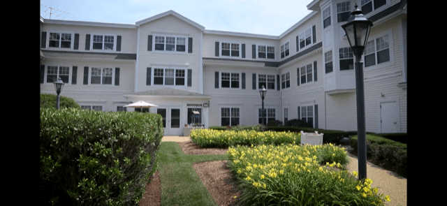 A multi-story residential building surrounded by a well-maintained garden.
