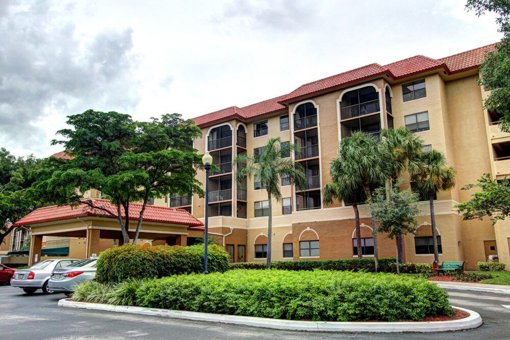 A multi-story residential apartment building surrounded by lush green landscaping.