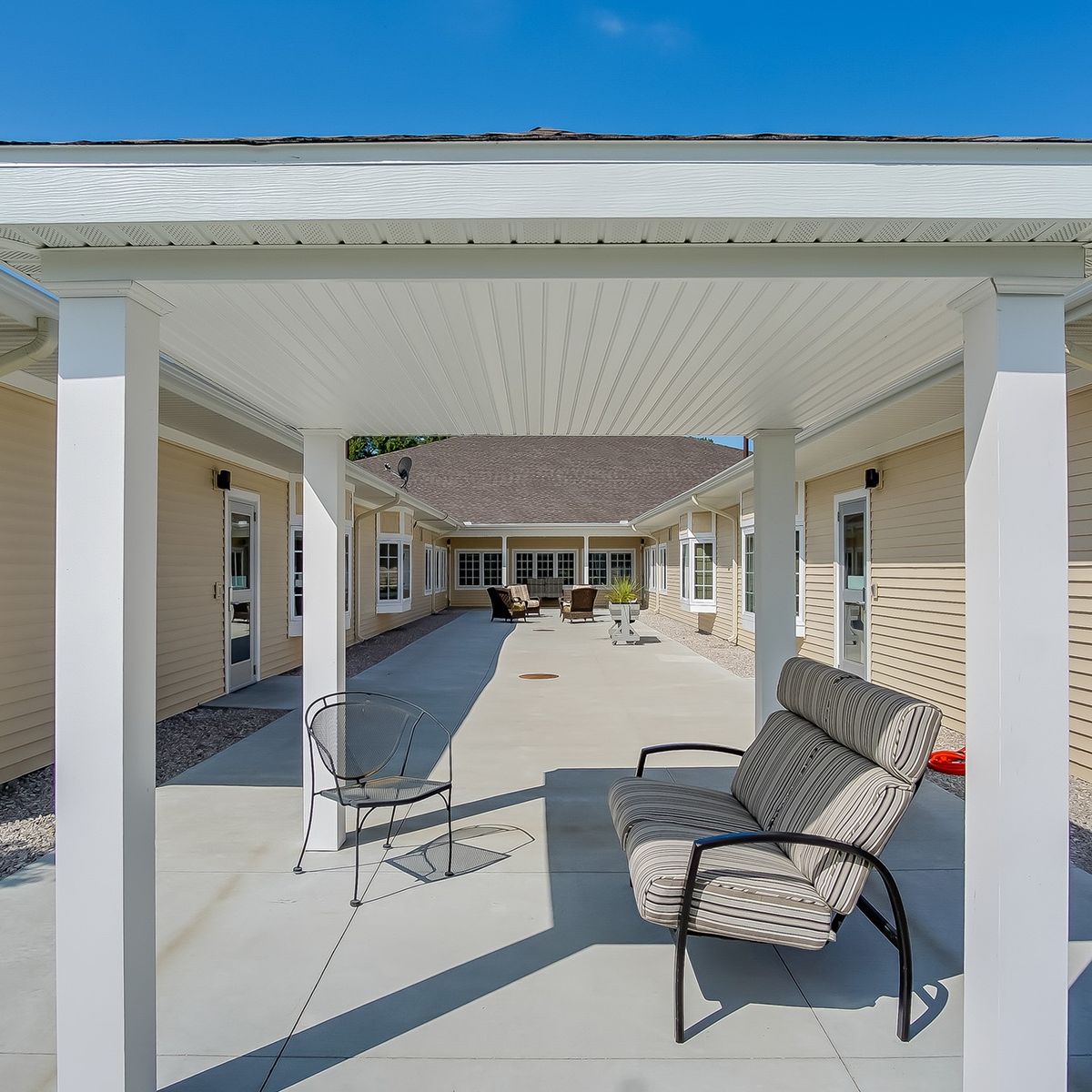 Outdoor patio area with seating under a pergola on a sunny day.