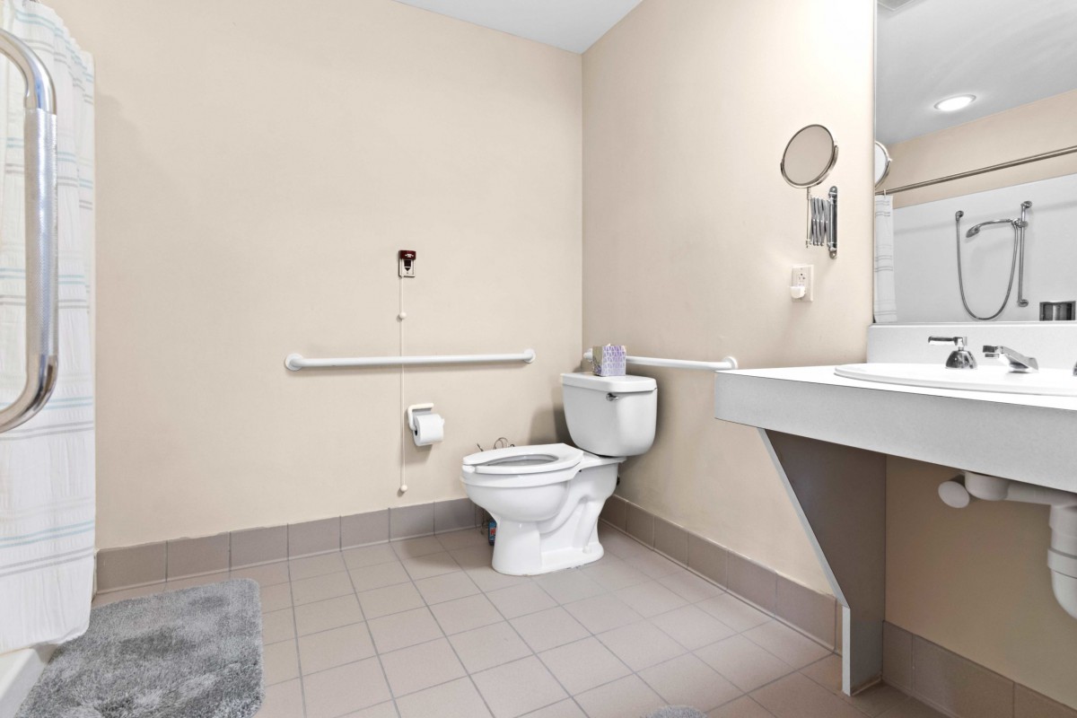 A clean bathroom with a toilet, sink, and handrail.