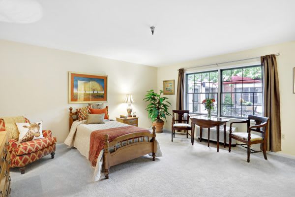 A cozy bedroom featuring a single bed and elegant furnishings with a large window providing natural light.
