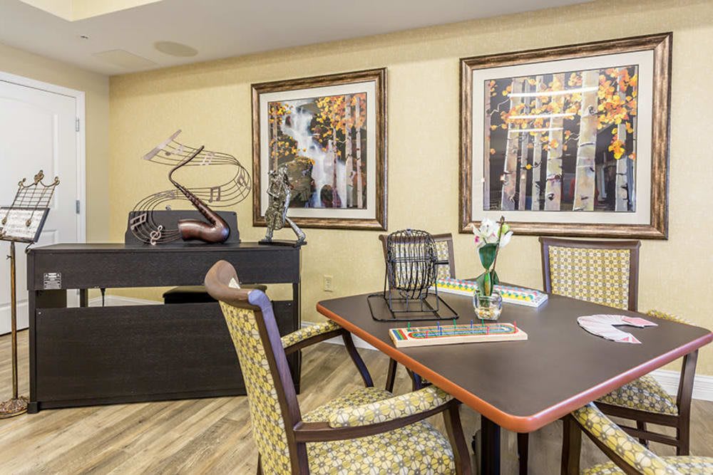 A modern dining room featuring a table with chairs, decorative sculptures, and framed artwork on the wall.