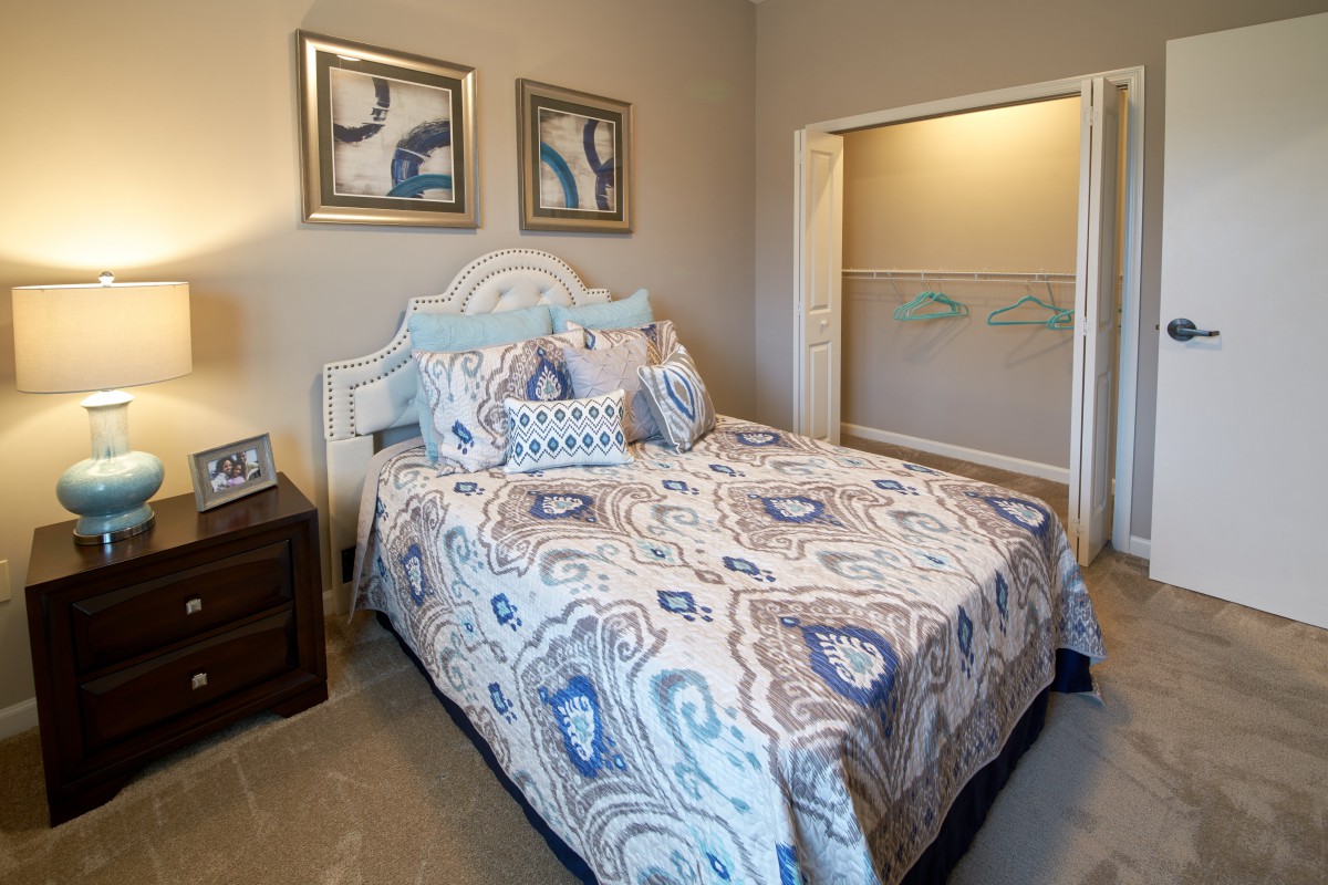 A cozy bedroom featuring a bed with patterned bedding and matching pillows, complemented by wall art and a bedside table.