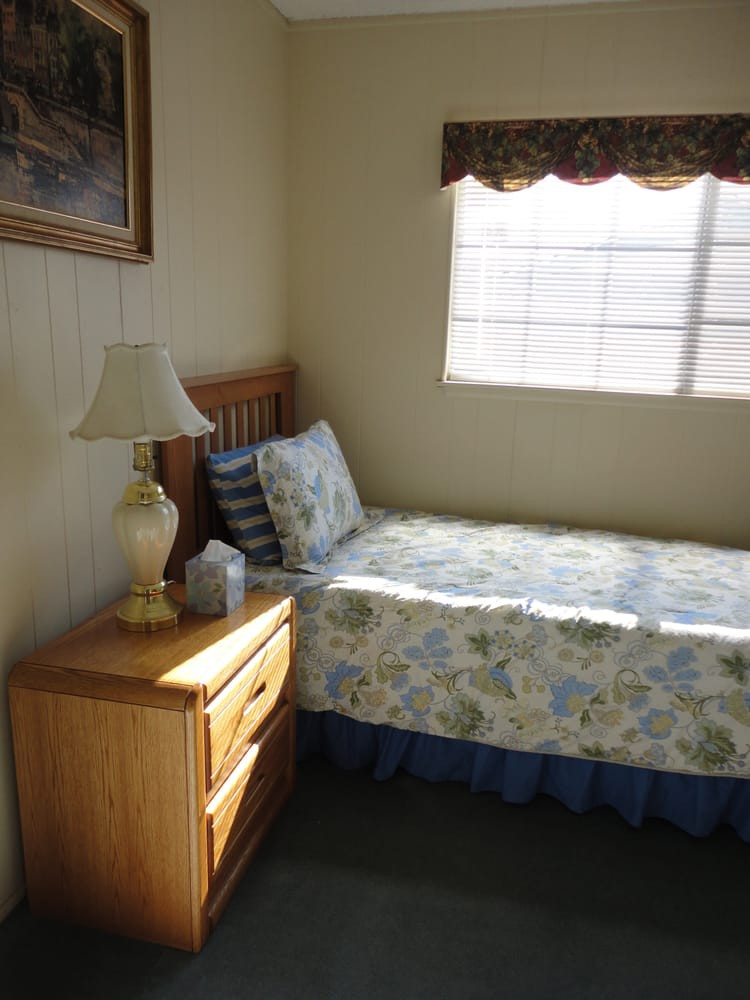 A cozy bedroom with a single bed and sunlight streaming through the window.