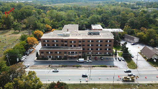 Aerial view of a hospital building surrounded by greenery and a road.