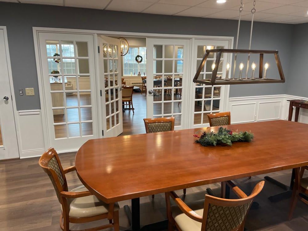 A stylish dining room with a wooden table and chairs, featuring glass doors and modern lighting.