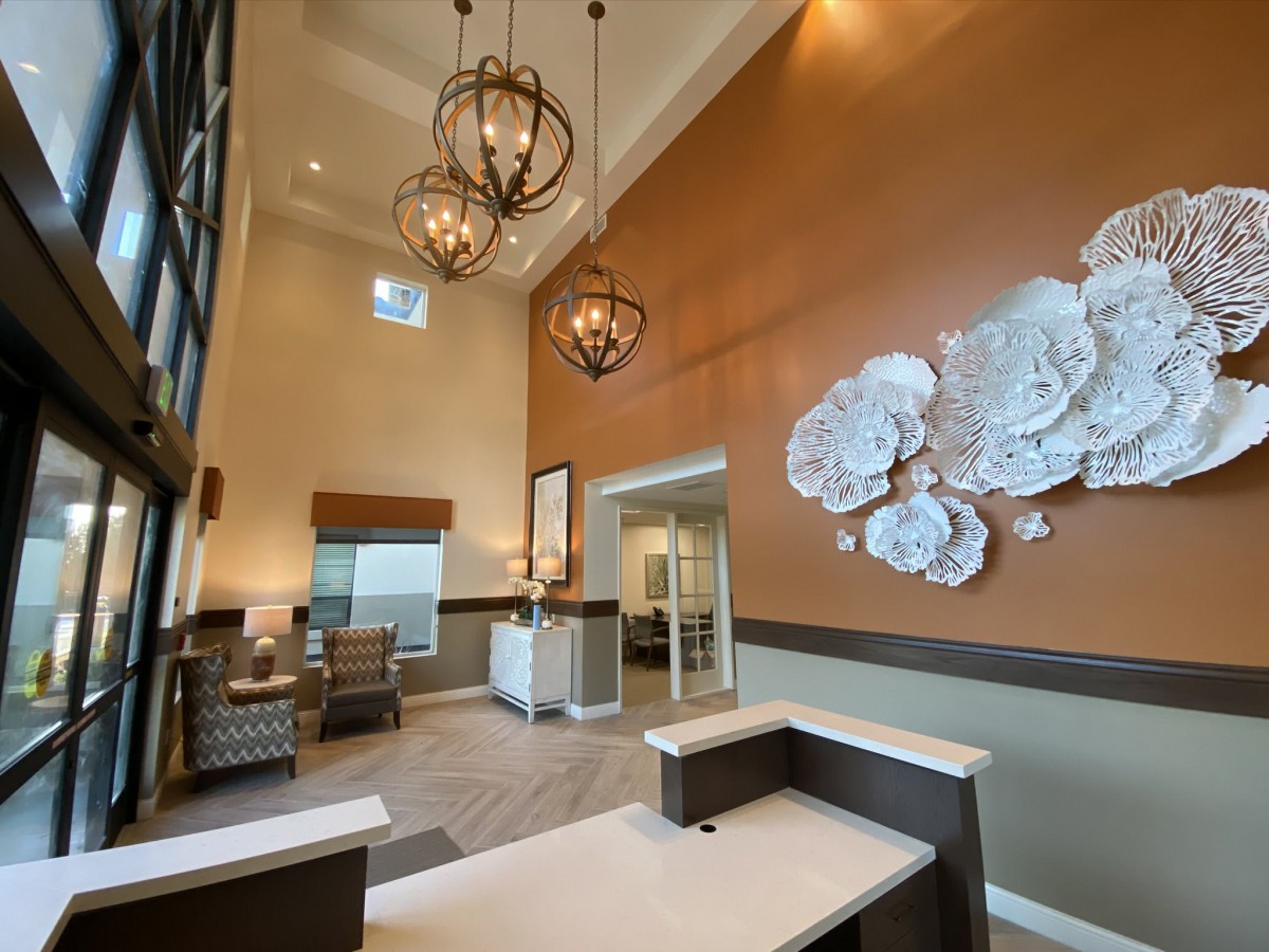 A modern lobby with high ceilings, stylish chandeliers, and decorative wall art.