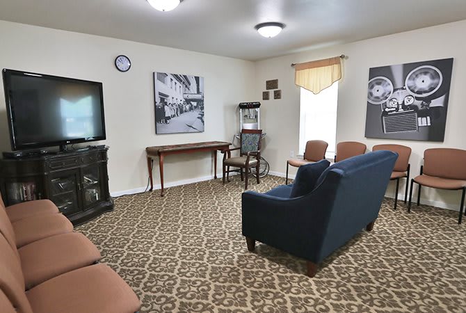 A cozy living room with comfortable seating, a television, and decorative wall art.