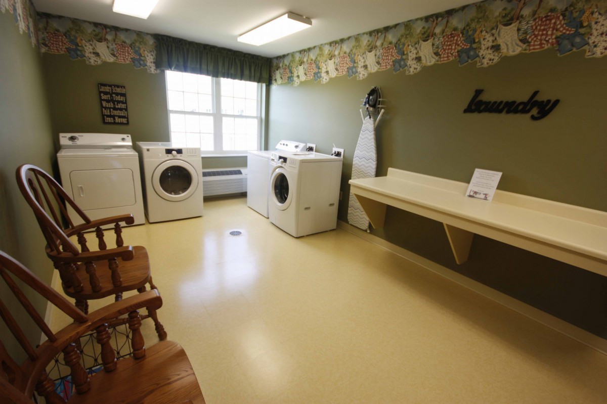 A laundry room with washers, dryers, and an ironing board.