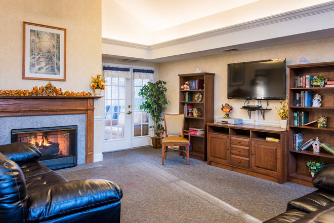 A cozy living room with a fireplace, television, and bookshelf.