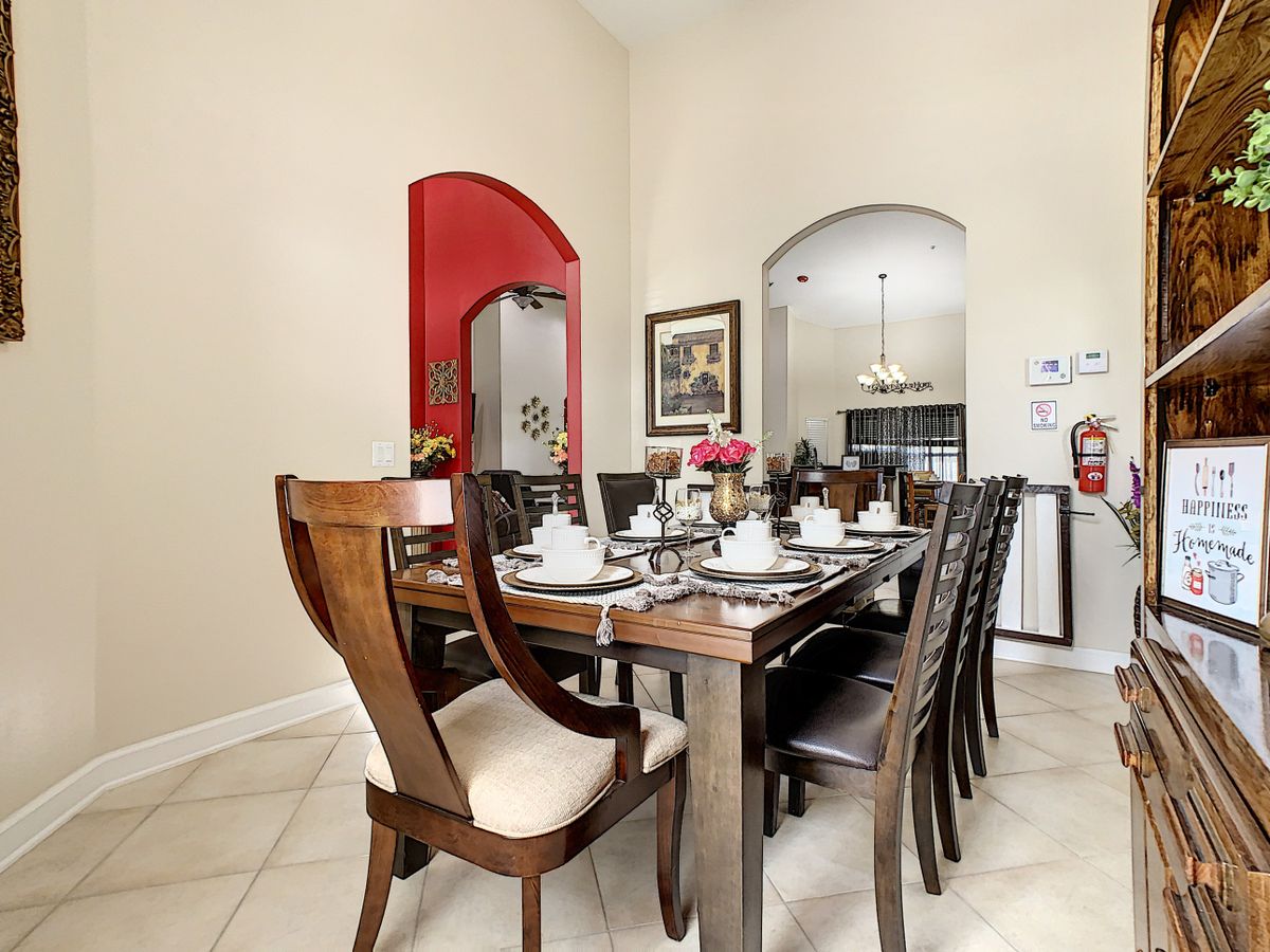 A well-appointed dining room featuring a large wooden table set for a meal, with elegant chairs and a view into the kitchen.