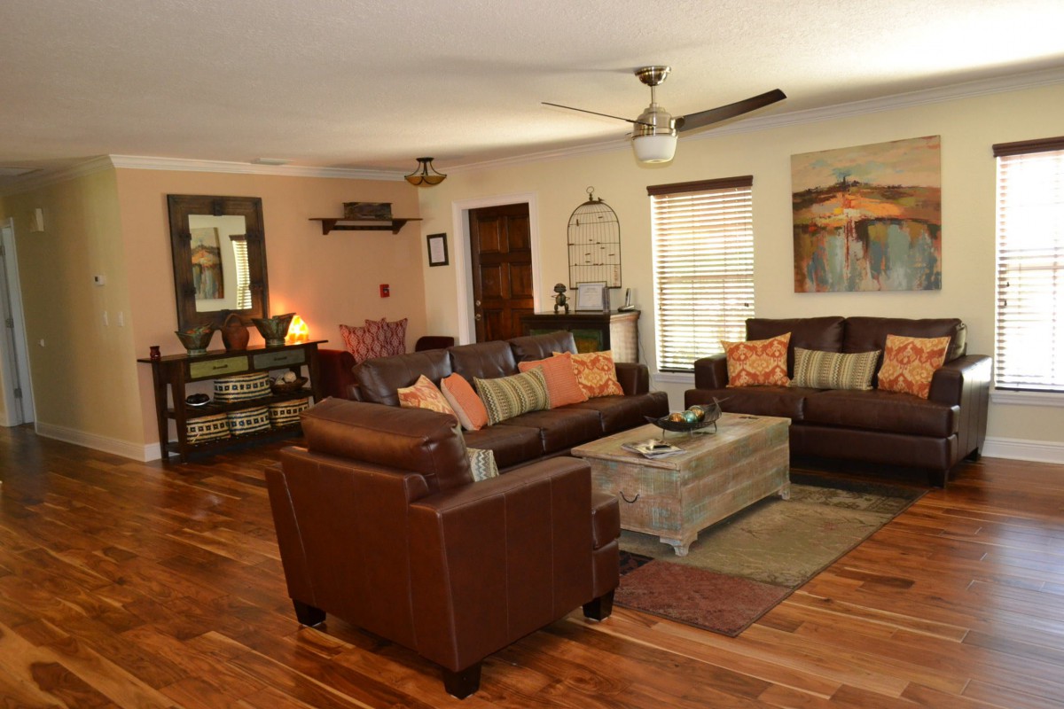 A cozy living room featuring leather sofas, wooden flooring, and warm decor.