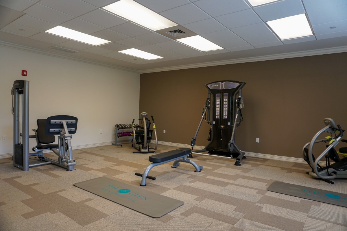 A small gym featuring various exercise equipment and a workout bench.