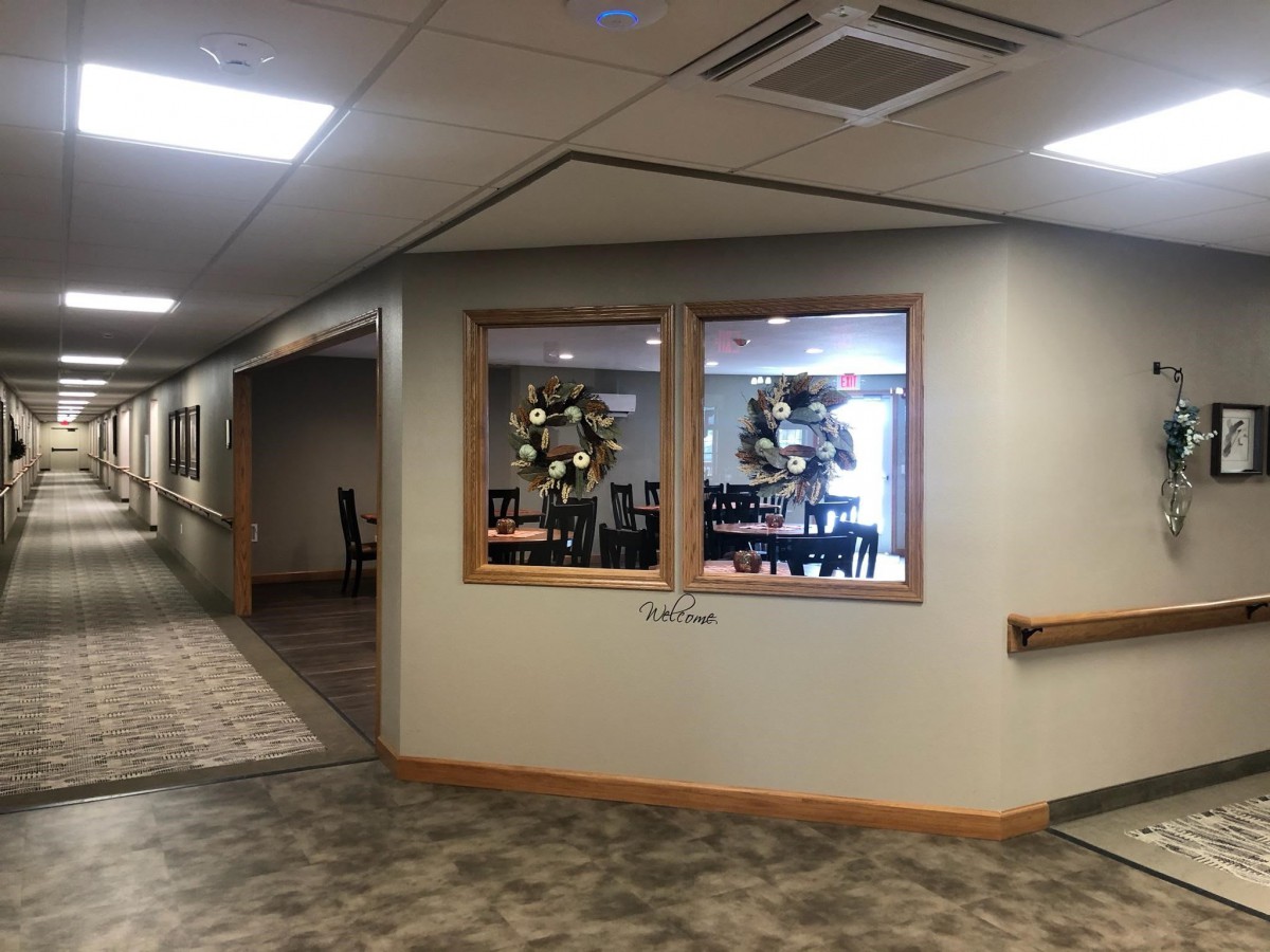 A hallway with windows showcasing a decorated dining area and ceiling lights.
