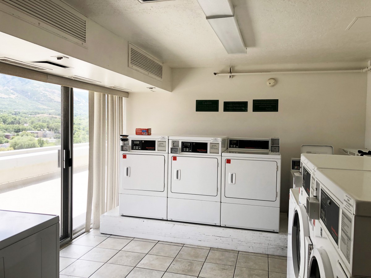 A bright laundry room featuring multiple washing machines and dryers.