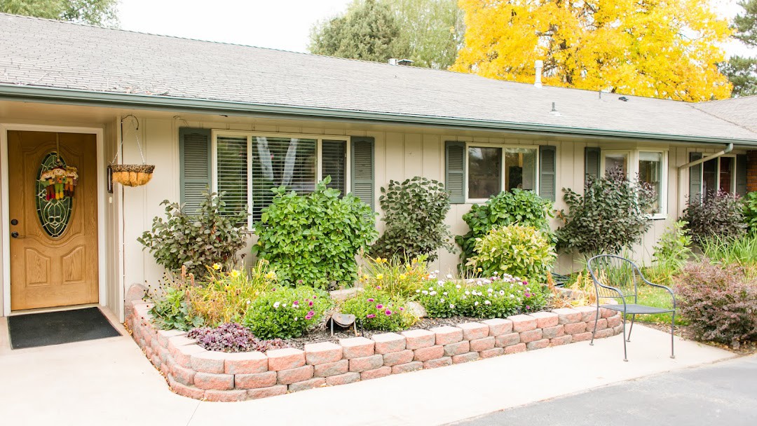 A house with a beautifully maintained garden featuring a variety of plants and flowers, bordered by bricks.