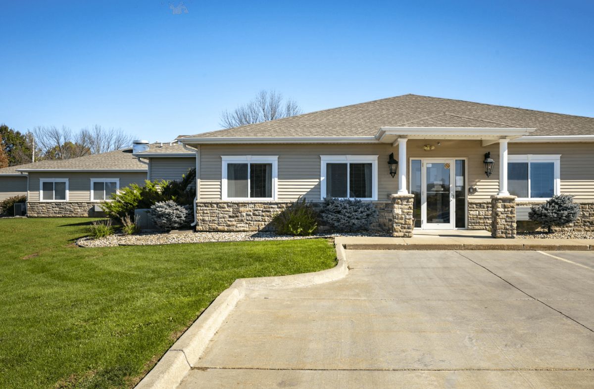 A suburban house with a driveway and well-maintained lawn under a clear blue sky.