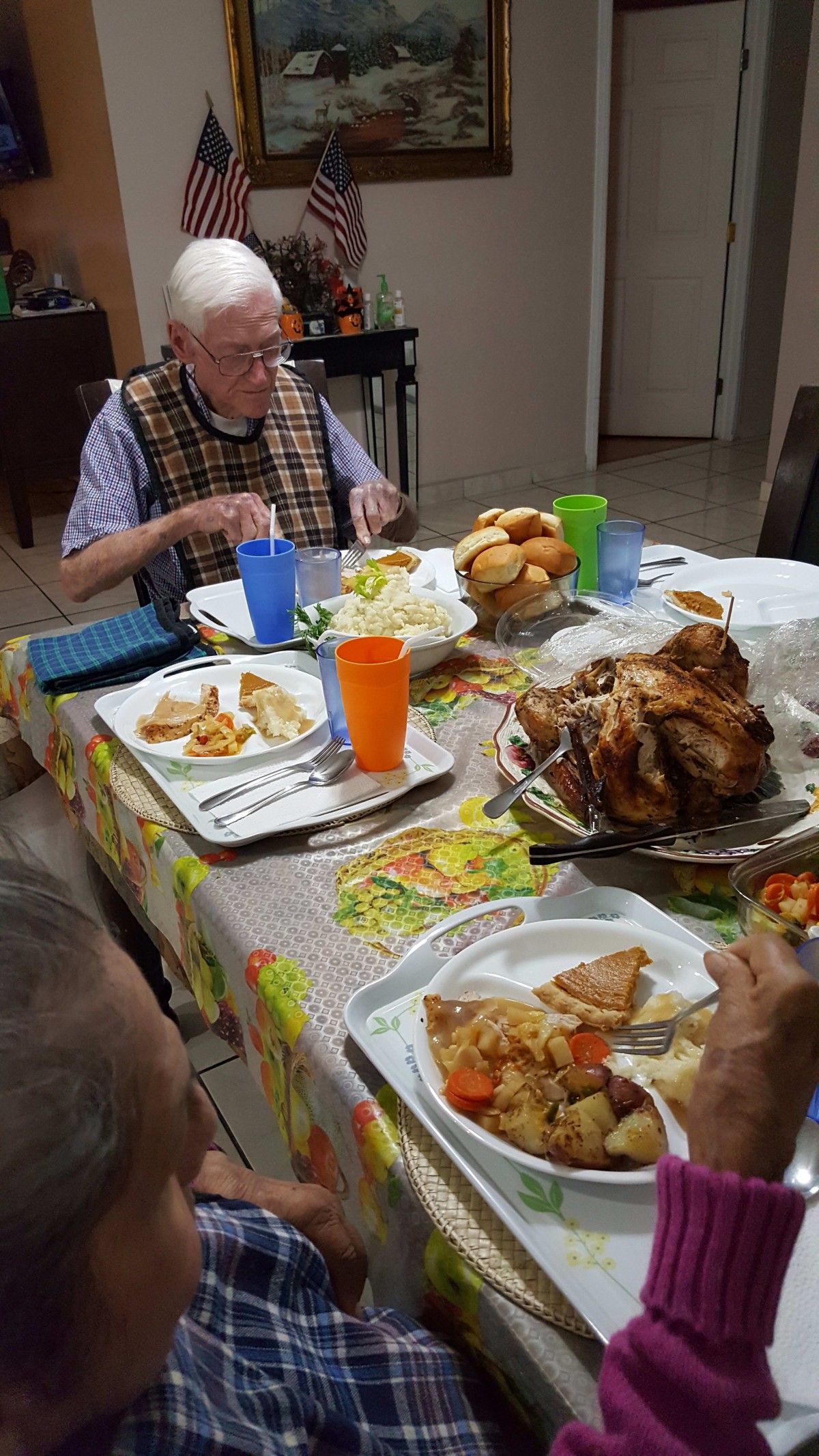 A family gathered around a table for a meal, featuring roasted chicken and various dishes.