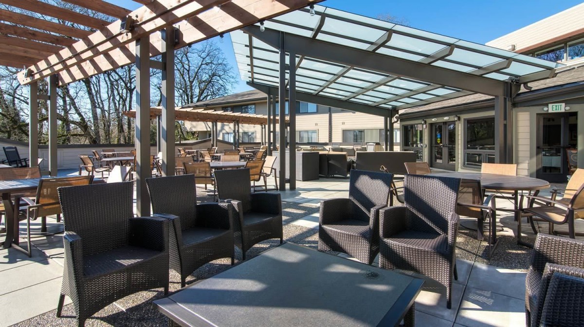 A stylish outdoor patio area featuring modern furniture under a pergola on a sunny day.