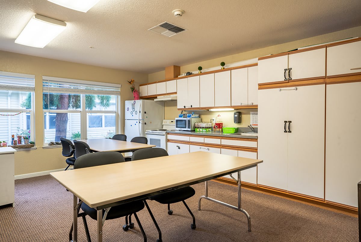 A shared kitchen and dining area with tables, chairs, and appliances.