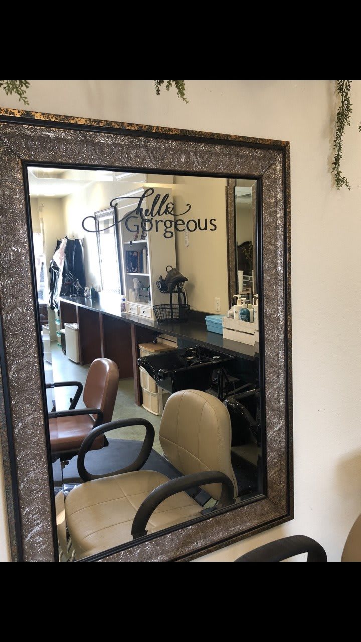 A salon interior featuring a large mirror and hairdressing chairs.