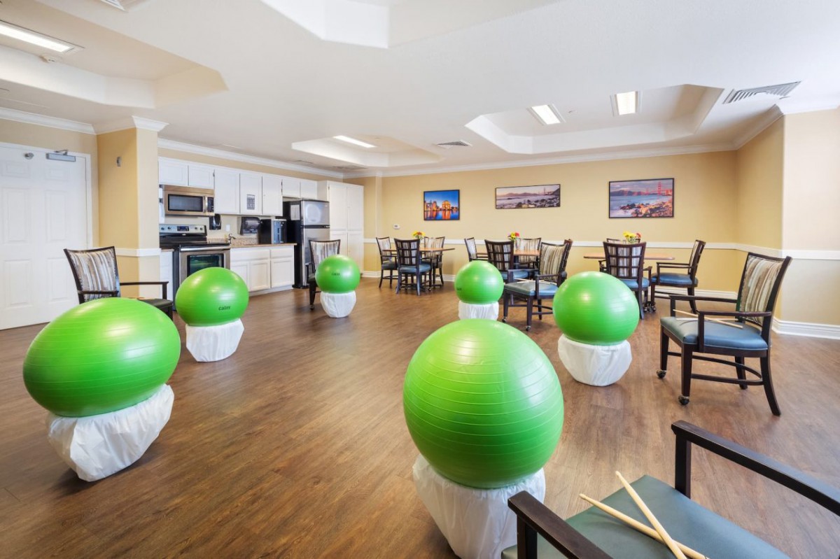A fitness room equipped with green exercise balls and drumsticks, featuring a seating area and wooden flooring.