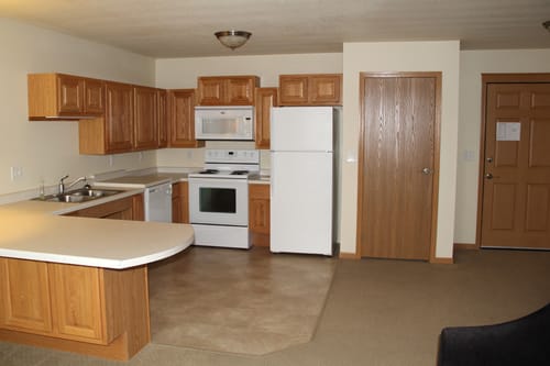 A kitchen with wooden cabinets, featuring a refrigerator, microwave, and oven.