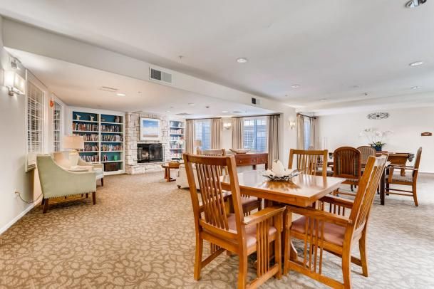A spacious and inviting living area featuring a dining table, comfortable seating, a fireplace, and bookshelves filled with books.