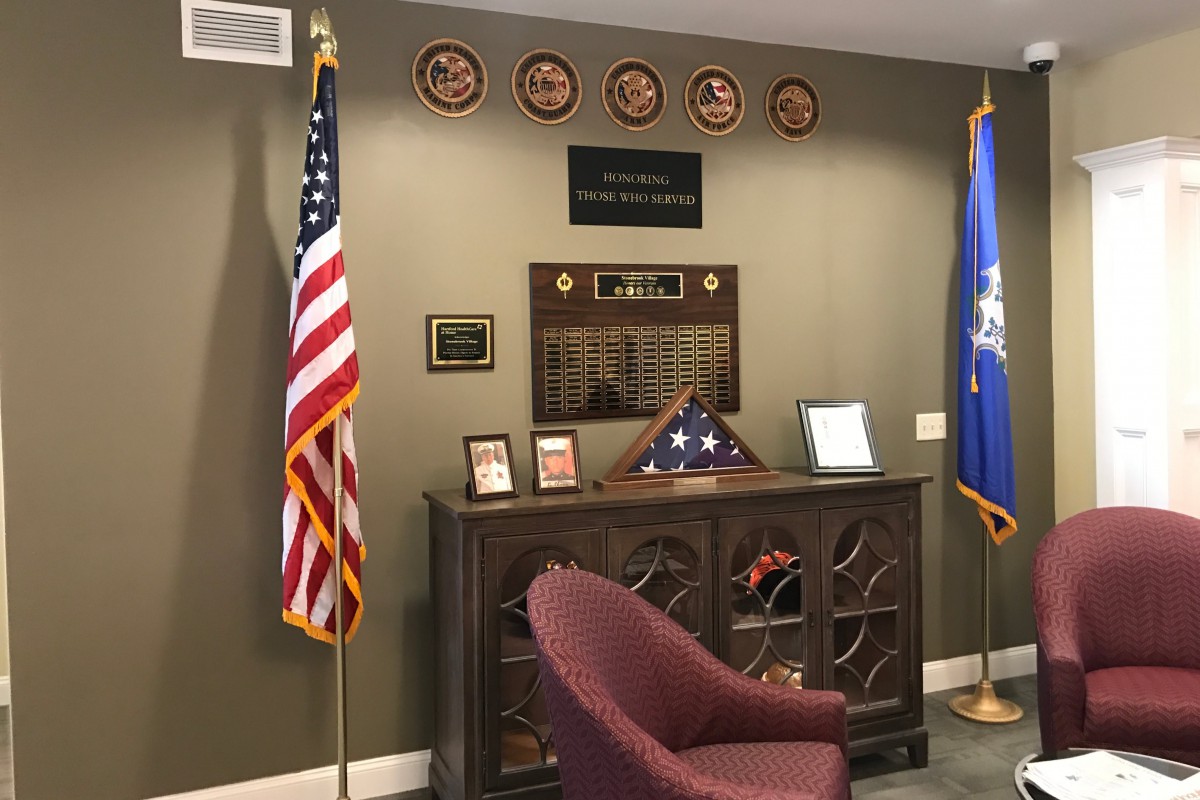 An office space adorned with military memorabilia, featuring flags, plaques, and a display case.