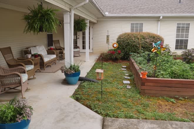 A cozy backyard patio with seating and a raised garden bed filled with plants.