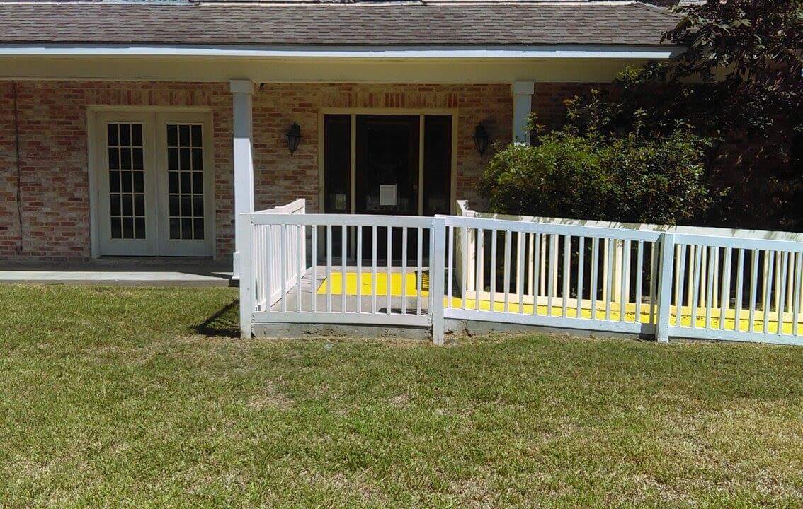 A house with a yellow ramp and white railings leading to the back patio.