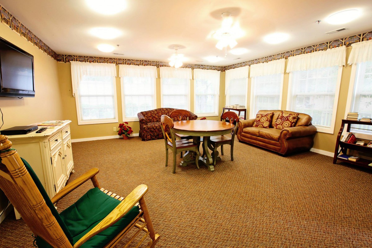 A cozy living room with multiple sofas, a round table, and large windows allowing ample natural light.