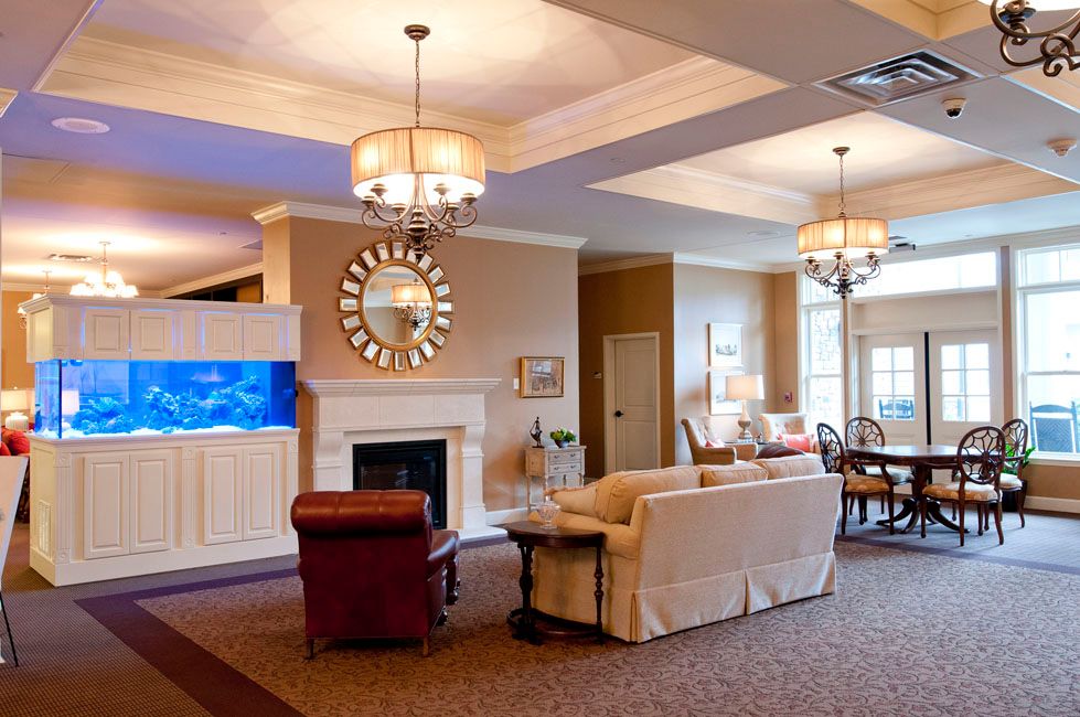 A modern living room featuring a comfortable seating area with a sofa, a fireplace, elegant chandeliers, and a wall-mounted television.