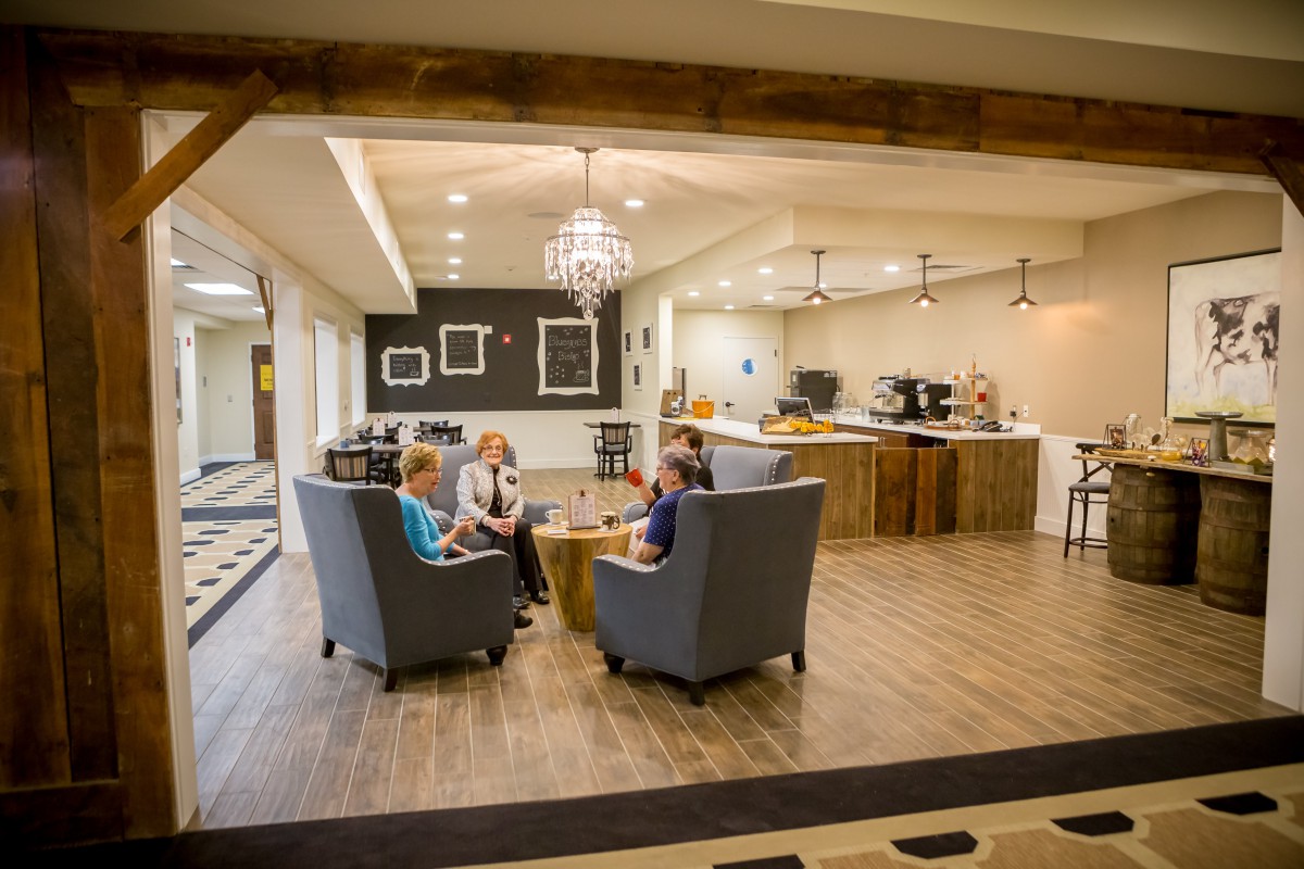 Three people sitting and conversing in a modern lobby area with stylish decor and ample lighting.