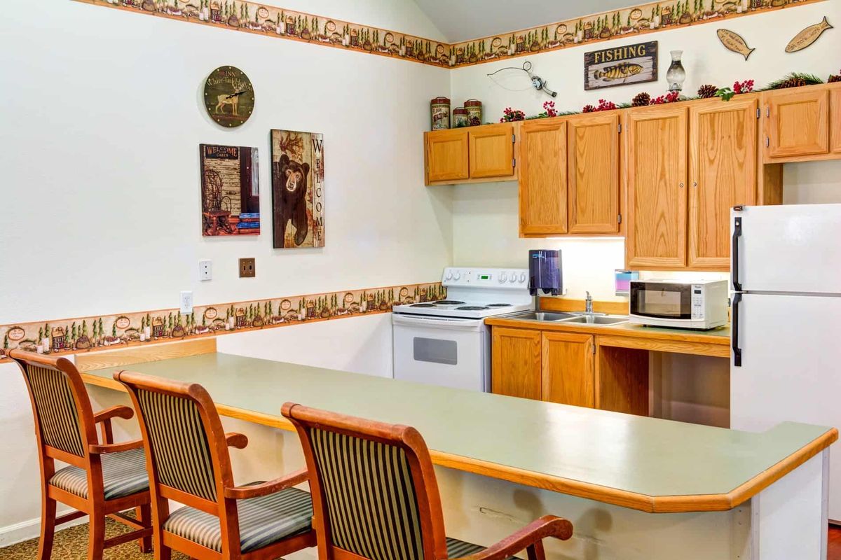 A cozy kitchen area with wooden cabinets, a stove, and a microwave, complemented by a counter with bar stools.