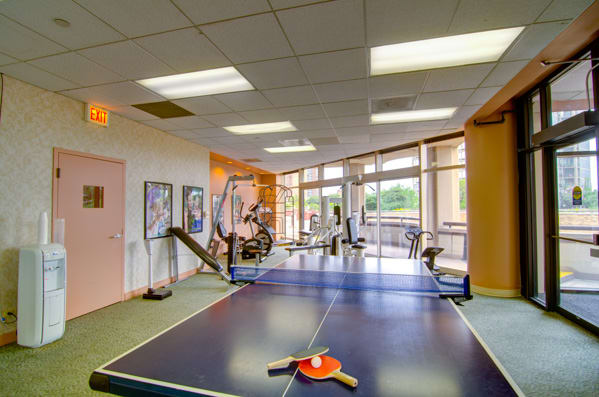 A fitness center featuring exercise equipment and a table tennis setup.