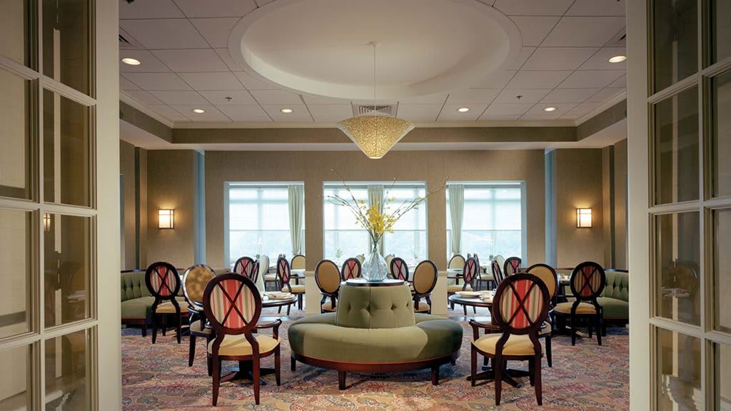 A well-lit dining room with elegant seating and a central chandelier.