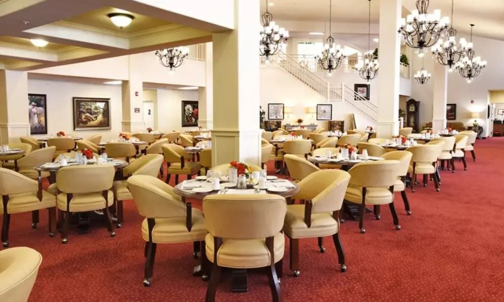 Elegant dining area featuring arranged tables and upholstered chairs with chandeliers hanging from the ceiling.
