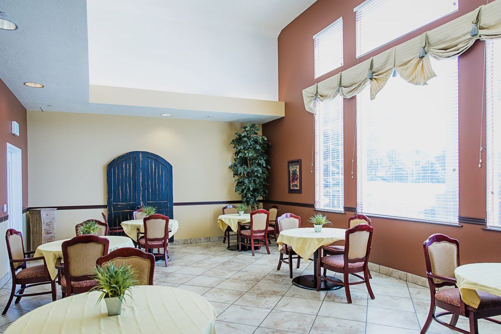 A bright and cozy dining area with several tables, chairs, and a large window allowing ample natural light.