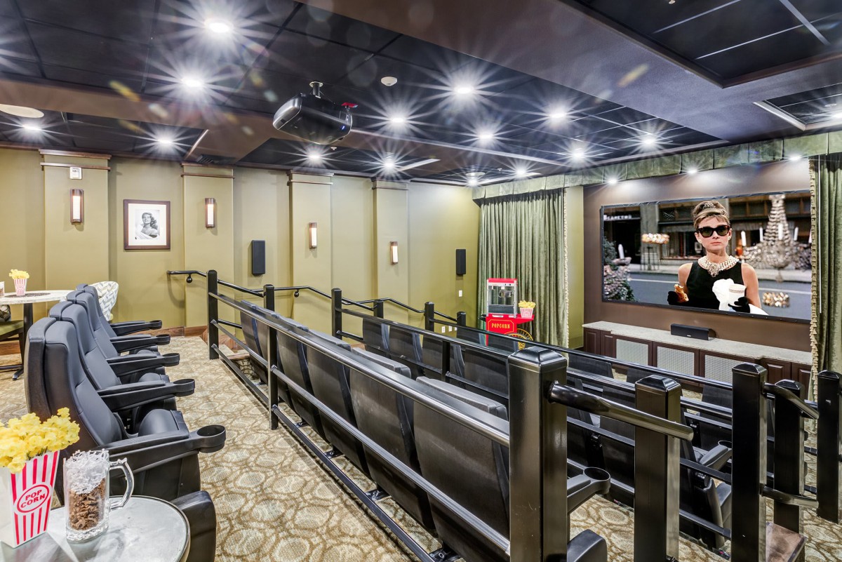 A luxury home theater room with tiered seating and a projector screen.