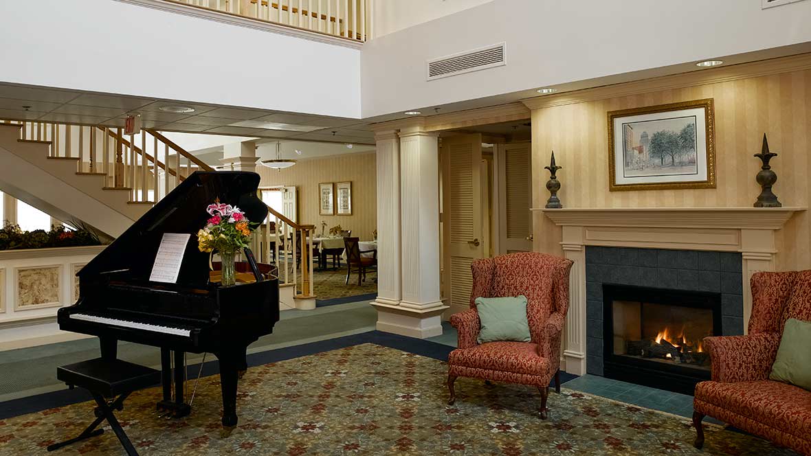 A cozy living room with a grand piano and a comfortable armchair by the fireplace.